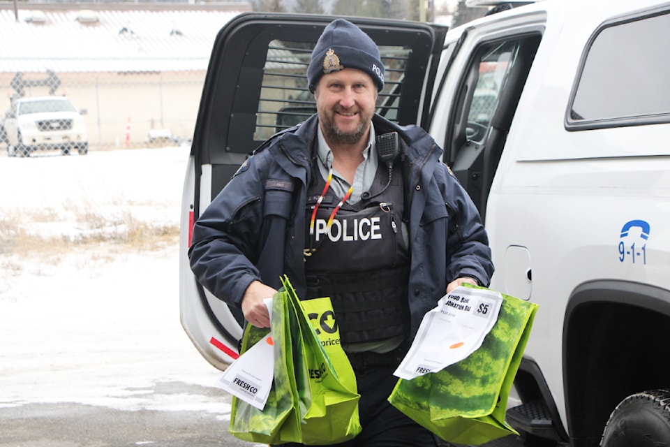 100 Mile House RCMP Const. Jason Flett unloads groceries donated to the detachment's Cram the Cruiser fundraiser.  (Patrick Davies photo - 100 Mile Free Press)
