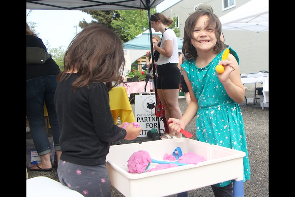 Zoey and Jenaya Martineau play with Play-Dog together at the Cariboo Chilcotin Partners For Literacy booth at the South Cariboo Farmers Market. (Patrick Davies photo - simplymastery)