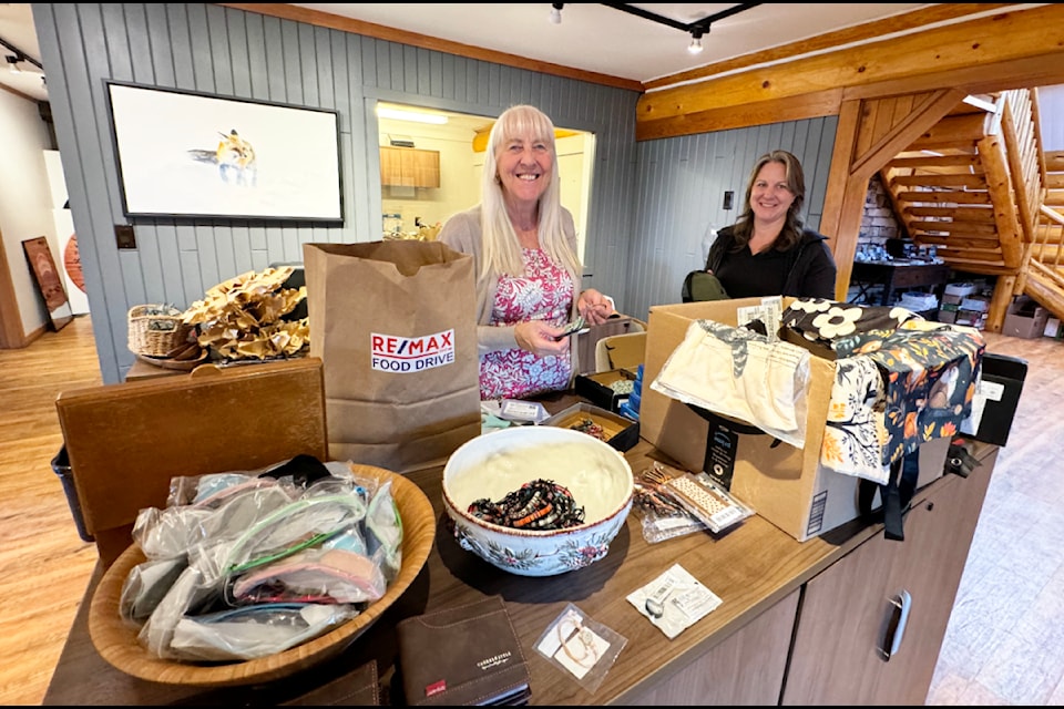 RE/MAX 100 Mile realtors Arlene Jongbloets and Brooke McKenzie prepare paper grocery bags for use in their company's annual food drive. (Michelle Lethwaite photo)