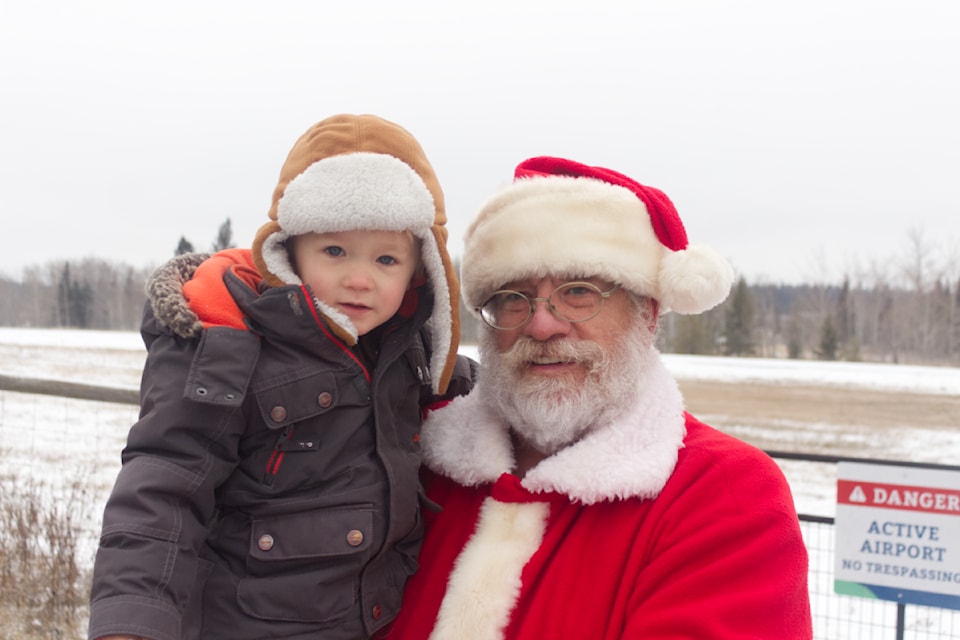 From left to right, Kaleb Mezaros, pictured next to Santa Claus at the 100 Mile Airport on Nov. 23 (Misha Mustaqeem - 100 Mile Free Press) 