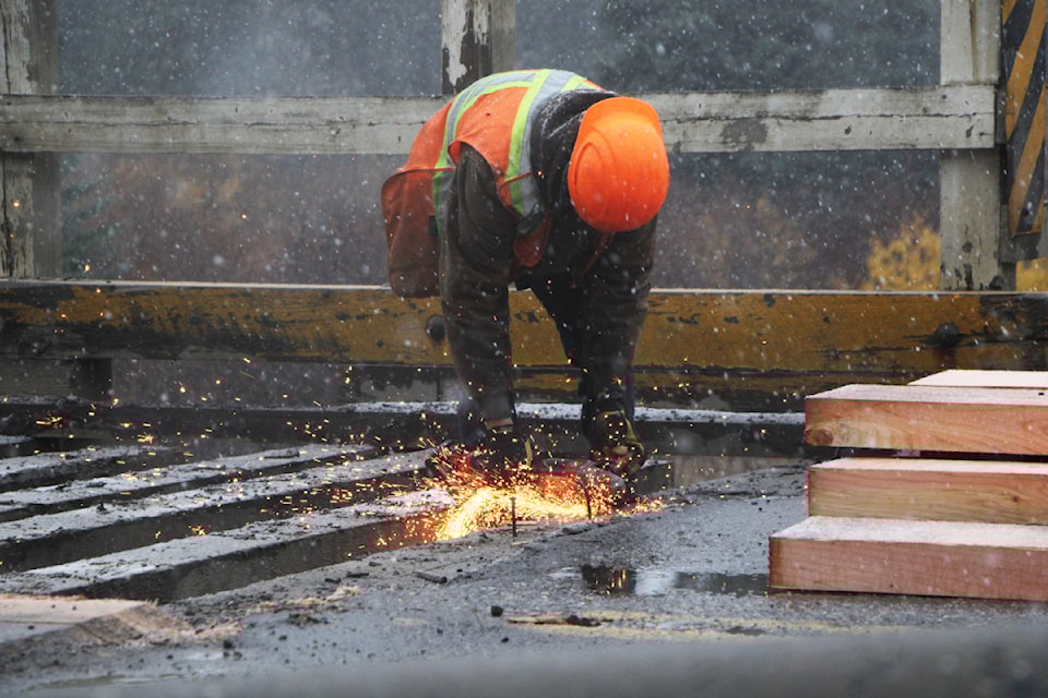 Dawson Road Maintenance worker Alex Bridgens uses an angle grinder to cut away the remaining nails embedded in Horse Lake Bridge ahead of a new surface of timber being added. The bridge is scheduled to be replaced in 2025. (Patrick Davies photo - simplymastery)