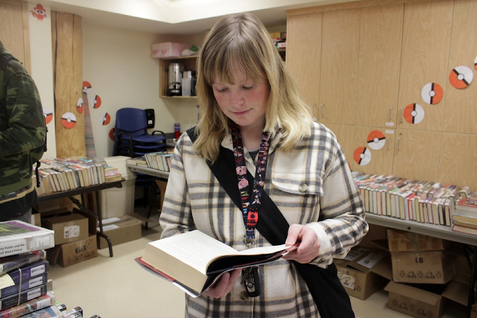 Rebecca Kingston reads over a book during the Fall Book Sale at the 100 Mile Library on Oct. 25. The book sale was really a clearance - by donation, people could pick whatever book they wanted out of the 100 Mile Library. (Misha Mustaqeem photo - 100 Mile Free Press)