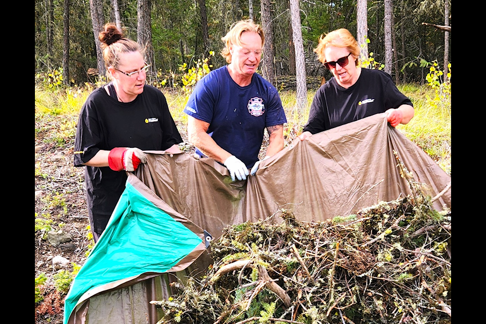 Lisa Graham, left, Thompson-Nicola Regional District FireSmart Coordinator Dan Funk and Bravo Neighbourhood Champion Pat Graham dumped a tarp full of woody debris that was later trailered to the 70 Mile Eco Depot for disposal during the Bravo Neighbourhood work bee on Sept. 24. (Ken Alexander photo)