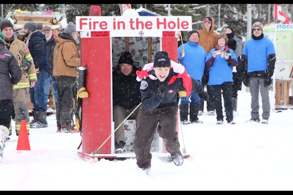 Tristan Reamsbottom grins as he pulls the Interlakes Volunteer Fire Department Outhouse while Mike Reamsbottom encourages him. (Patrick Davies photo - 100 Mile Free Press)