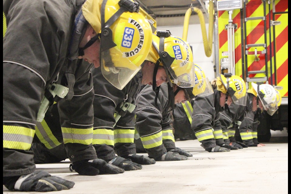 100 Mile Fire Rescue members buckle down and do some pushups on Wednesday, Feb. 19 2025. (Patrick Davies photo - 100 Mile Free Press)