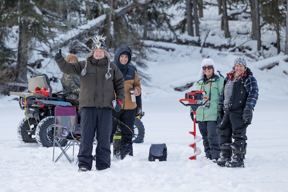Participants of the  Fishing Highway 24 Tourist Association's Ice Fishing Derby on Sheridan Lake gather around an auger as they prepare to try their luck at ice fishing. (Nikki Pixs Photography)