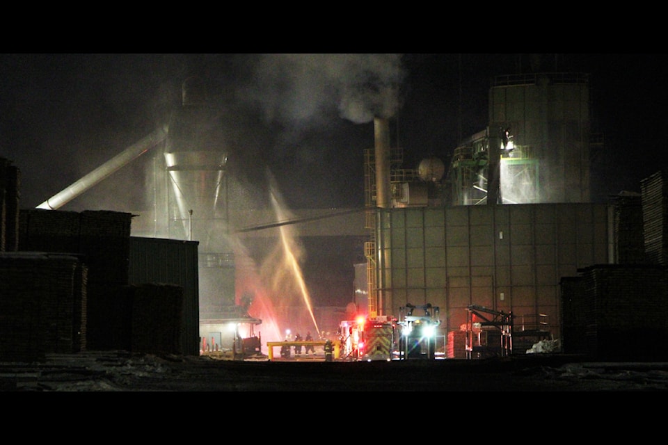 Members of 100 Mile Fire Rescue spray water on a silo at West Fraser 100 Mile and nearby outbuildings in an attempt to extinguish a silo fire. 100 Mile Fire Rescue and West Fraser employees were able to extinguish the fire within an hour of it being reported. (Patrick Davies photo - simplymastery)
