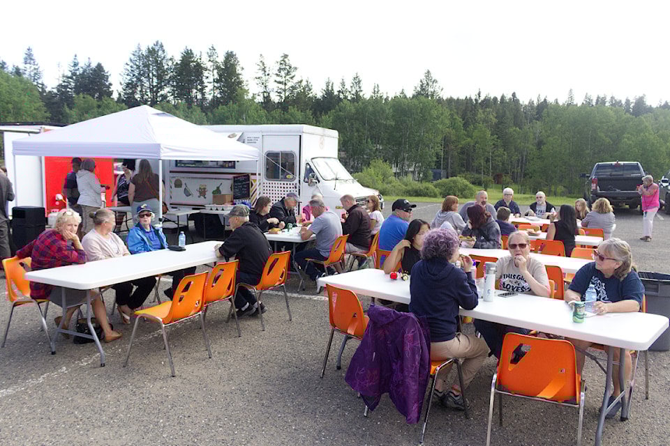 People sit and eat food during the Food Truck festival at the 108 Mile Community Hall on Saturday, June 28. (Misha Mustaqeem photo - simplymastery)