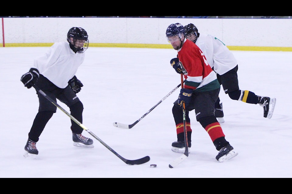 The Teachers and Grads fight for control of the puck during Peter Skene Ogden Secondary School's Grads vs Teachers Hockey Game. (Patrick Davies photo - 100 Mile Free Press)