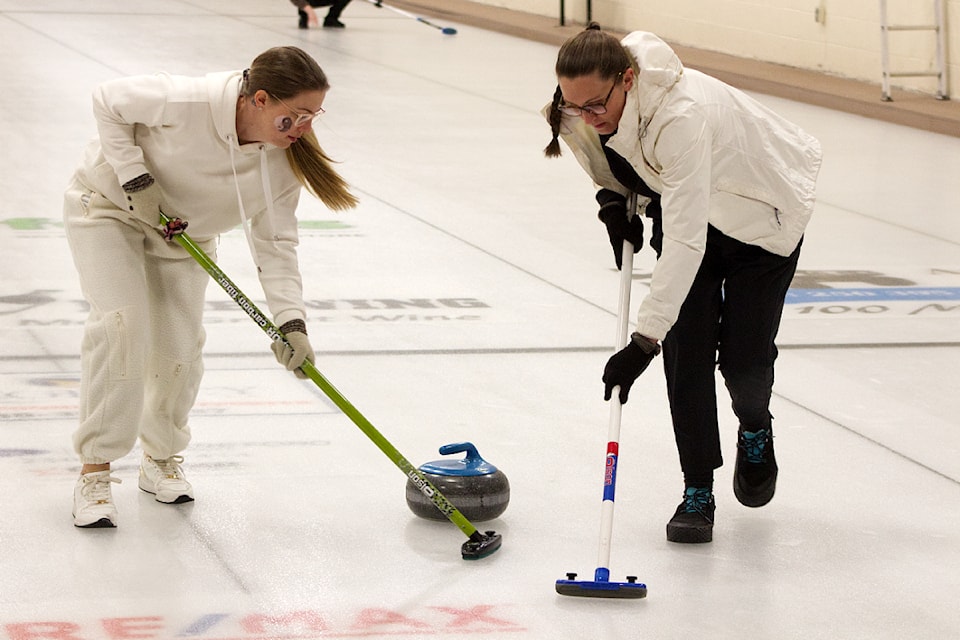 Christine Law and Laurie Sehn both do some sweeping during the 100 Mile Curling Club's Women's Bonspiel held at the 100 Mile Curling Club on March 1. (Misha Mustaqeem photo - simplymastery)