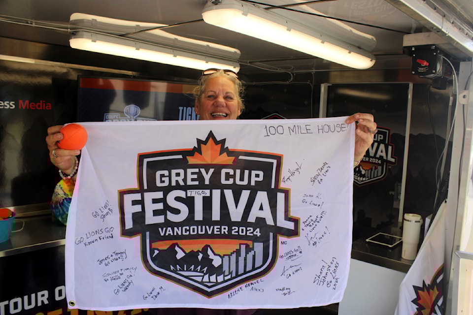 Shelly Brooke holds up a flag containing signatures of people from 100 Mile House at the Grey Cup festival truck. The flags will be presented during the Grey Cup, which is scheduled to be held in Vancouver on Nov. 17. (Misha Mustaqeem photo - 100 Mile Free Press) 