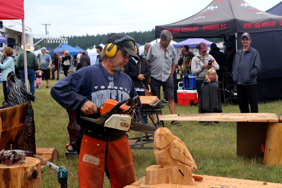 Hannu Yliruusi, a carver, carves an owl as onlookers look on during the 2024 South Cariboo Garlic Festival at Lac La Hache (Misha Mustaqeem photo - 100 Mile Free Press)