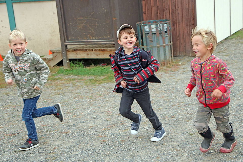 Emery Levermann (from left) runs beside the 100 Mile House Elementary School playground with his friends Thibault Feissli and Quinton Philip. (Patrick Davies photo - 100 Mile Free Press)