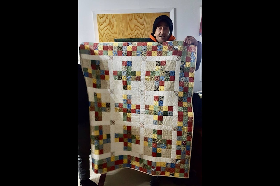 Chris Warren, with his “comfort” quilt, donated by the Log Cabin Quilters on the loss of his home. (Diana Forster photo).