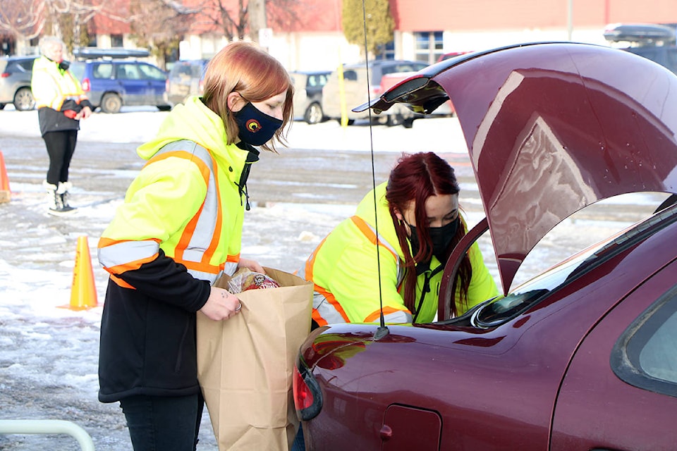 Serina Kary and Tristine Jones load up a car with food from the 100 Mile House Foodbank Society. (Patrick Davies photo - 100 Mile Free Press)