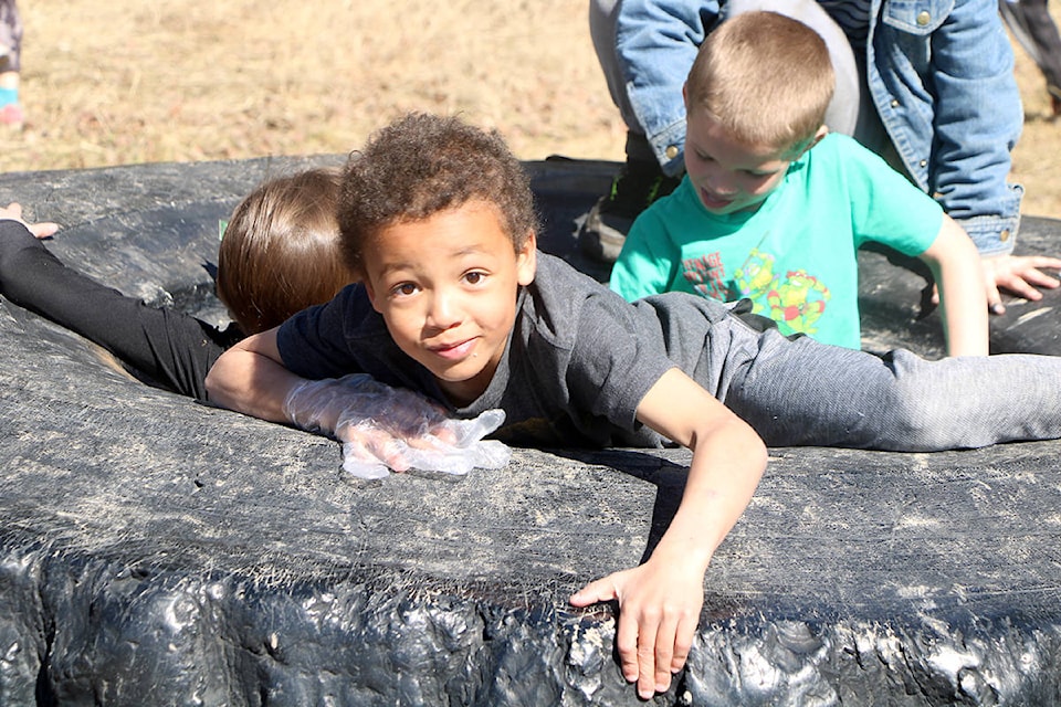 Horse Lake Elementary’s Elijah Ratcliff and Reid Milward climb inside a tire looking for garbage during an Earth Day cleanup. (Patrick Davies photos - 100 Mile Free Press)
