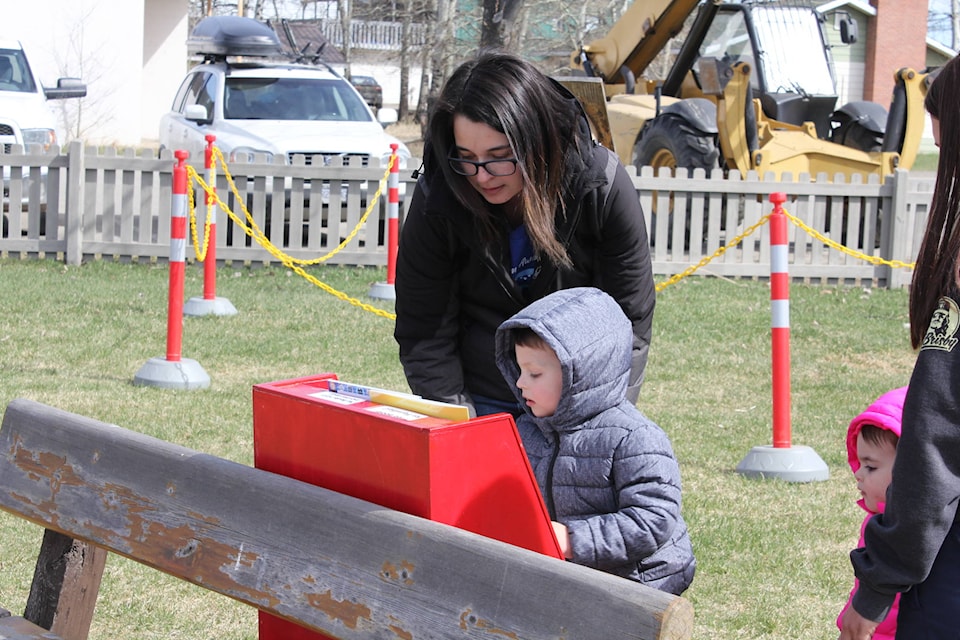 Courtney Debruycker and her son, John, pick out a free book from the Bright Red Bookshelf at the Autism Awareness Walk at the South Cariboo Visitor Centre April 23, 2021. (Melissa Smalley photo - 100 Mile Free Press)
