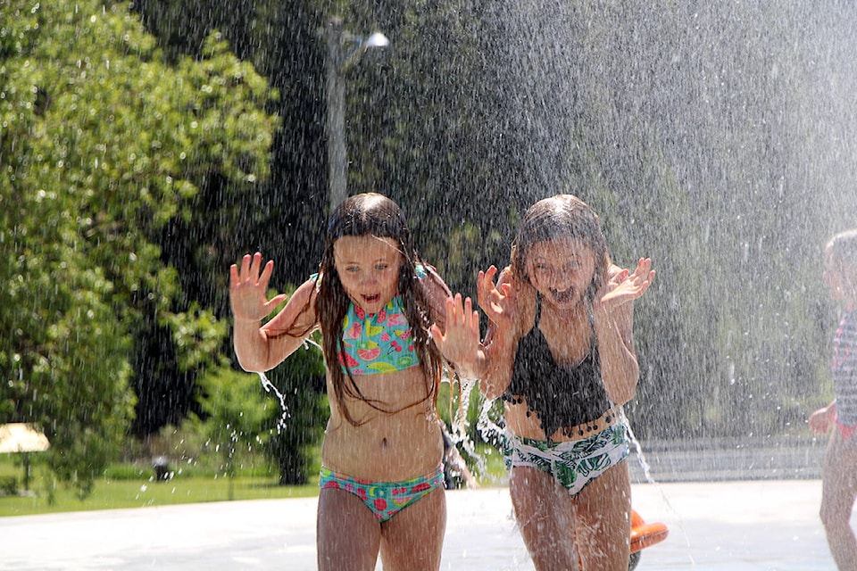 Olivia Szatmari and Ava Rywaczuk screech after getting soaked by a bucketful of water at Centennial Park’s spray park. (Patrick Davies photo - 100 Mile Free Press)