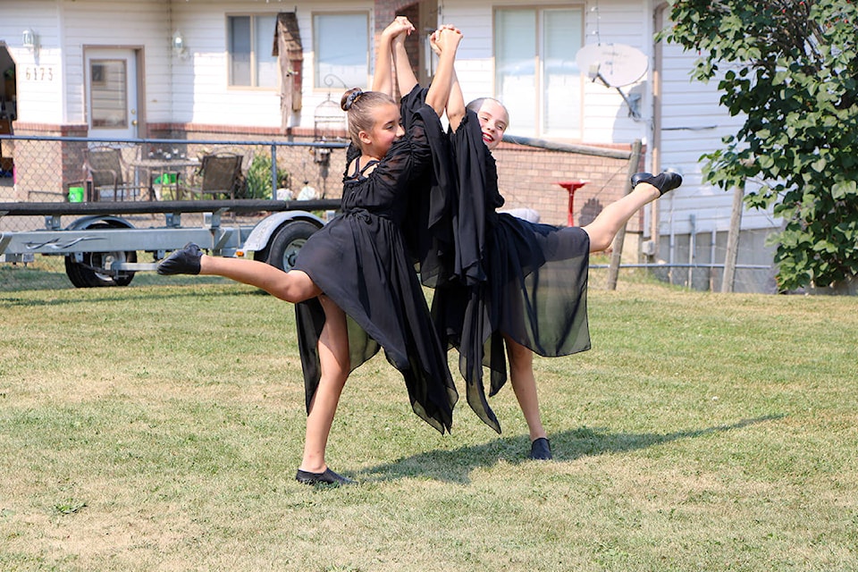 Sophia Caetano and Cheney Langley dance together to entertain neighbours at a fundraiser barbeque for B.C. firefighters. (Patrick Davies photo - 100 Mile Free Press)