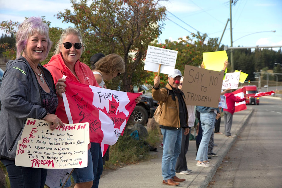 Debra McLean, and Gloria Coburn, joined about 100 people Monday on Highway 97 in 100 Mile House to protest B.C.’s vaccine passport mandate. (Kelly Sinoski photo - 100 Mile Free Press).