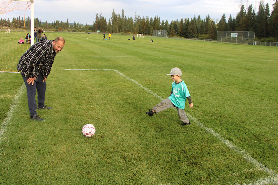 100 Mile House Soccer Association coach Jeff Martens smiles as player Malikai Frank takes a shot against him on net. (Patrick Davies photo - 100 Mile Free Press)