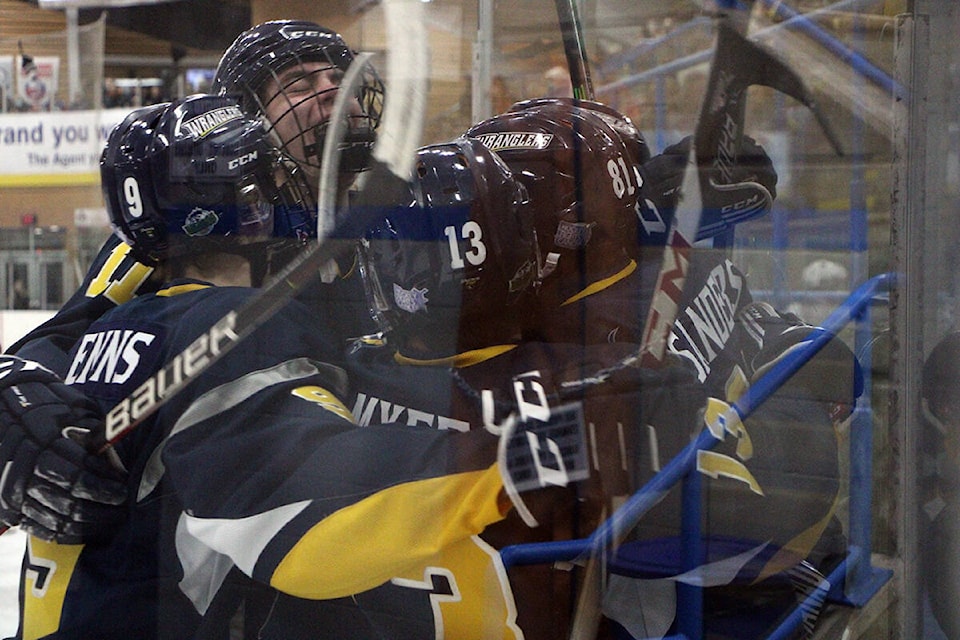 The 100 Mile House Wranglers pile up against Ethan Sanders after he scored the first goal of the game early in the first period Friday night. (Patrick Davies photo - simplymastery)