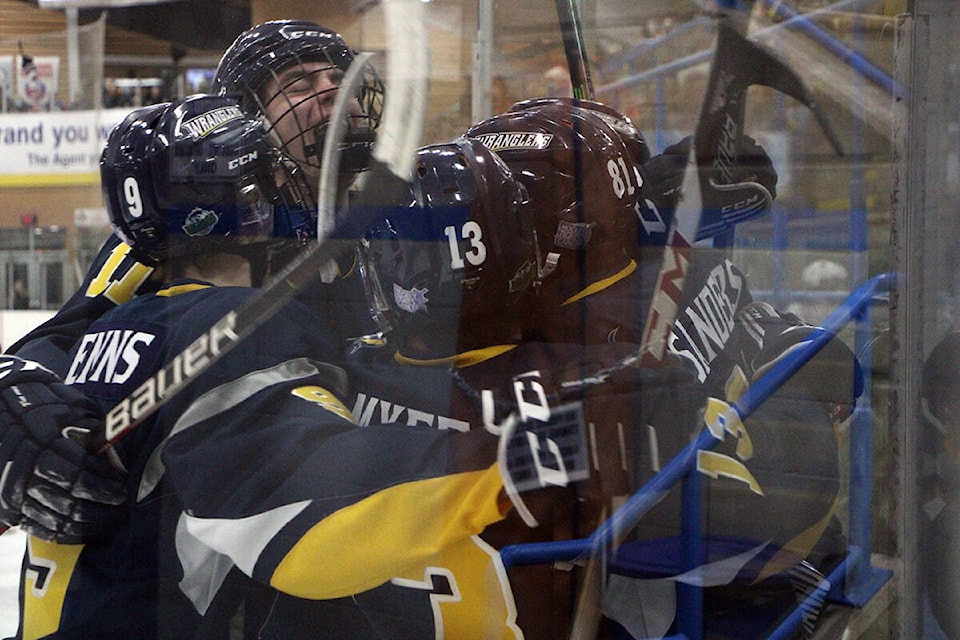 The 100 Mile House Wranglers pile up against Ethan Sanders after he scored the first goal of the game early in the first period Friday night. (Patrick Davies photo - 100 Mile Free Press)