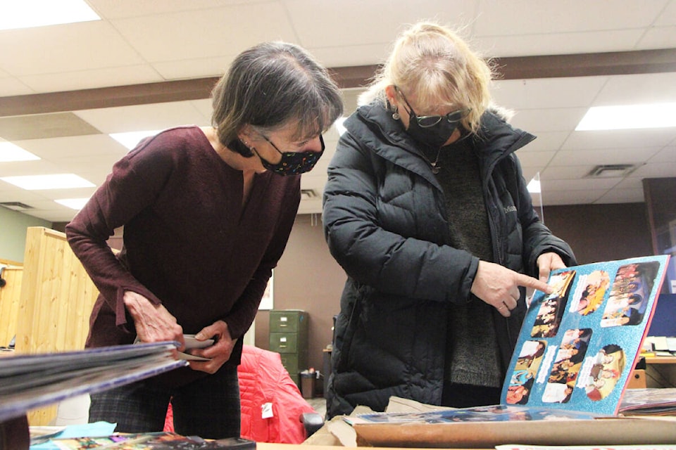 Karen Smith and Margot Shaw, some of the 100 Mile Performing Arts Society’s most active members, pour over pictures from their favourite shows at the Free Press office. (Patrick Davies photo - 100 Mile Free Press)