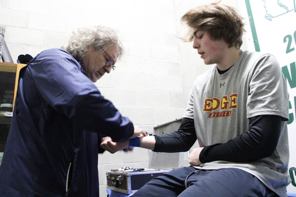 100 Mile House Wrangler trainer and physiotherapist Rainer Meyer tapes the wrist of Chase Sitarski before a game against the Revelstoke Grizzlies. (Patrick Davies photo - 100 Mile Free Press)