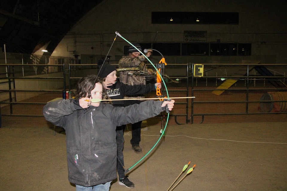 Freddie Boutilier aims downrange with her brother Oscar Boutilier and their father Mike Boutilier at last Wednesday’s Bighorn Archery Club shoot. (Patrick Davies photo - simplymastery)