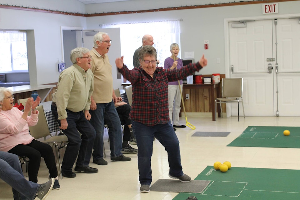 Dot Verboom celebrates - as teammates look on in awe - after a successful delivery during a carpet bowling match at Creekside Seniors Centre. (Melissa Smalley photo - 100 Mile Free Press)