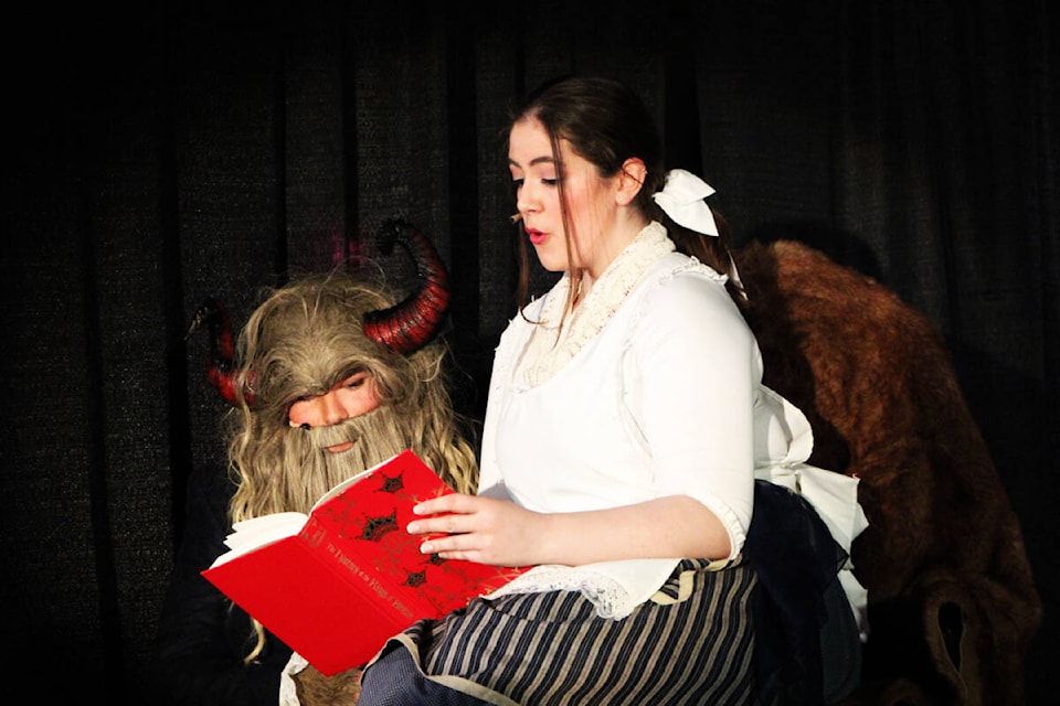 Evan Kalmakoff’s Beast peers over the shoulder of Melody Watkins’ Belle as she reads him the Legend of King Arthur. (Patrick Davies photo - 100 Mile Free Press)