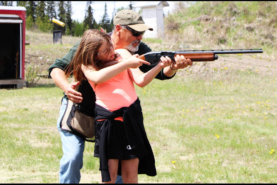 George Ostoforoff helps Macy Cunnigham keep a shotgun steady as she fires it last Saturday. (Patrick Davies photo - 100 Mile Free Press)