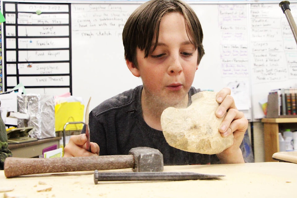 Declan Kerr blows dust off of his sculpture while learning how to carve soapstone at Horse Lake Elementary School. (Patrick Davies photo - 100 MIle Free Press)