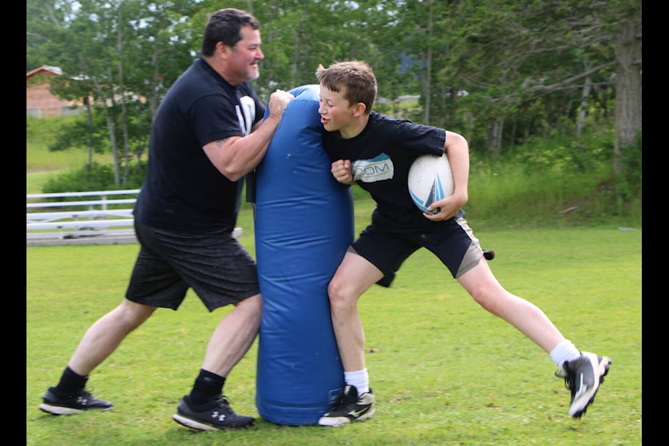 Brodie Pecor slams into a practice pad held by his dad Paul Pecor while taking part in a rugby practice last week. (Patrick Davies photo - 100 Mile Free Press)