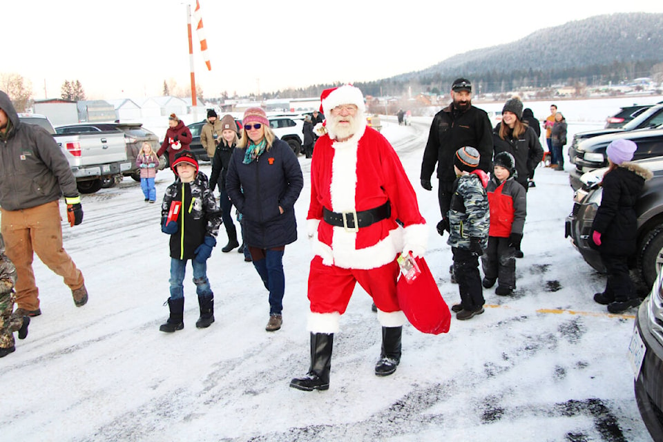 Santa Claus leads a crowd of children and parents to the South Cariboo Rec Centre for a meet and greet last Friday. (Patrick Davies photo - 100 Mile Free Press)