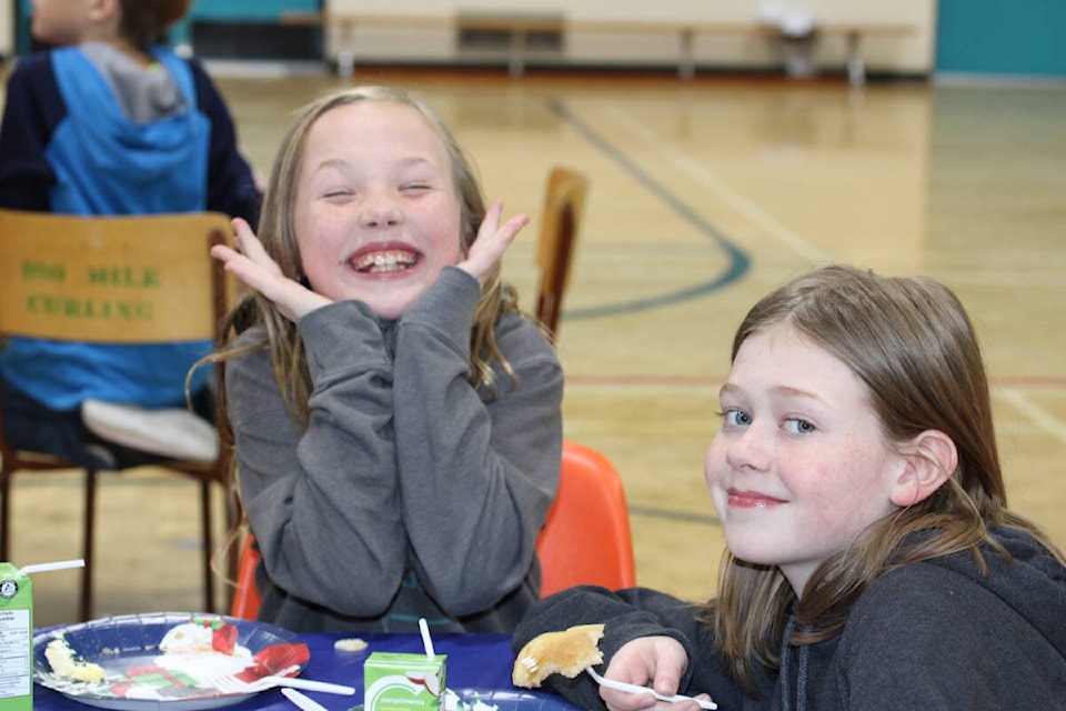 Naty Law (L) grins as she and her friend Weslie Martens enjoy their breakfast. (Fiona Grisswell photo - 100 Mile Free Press)