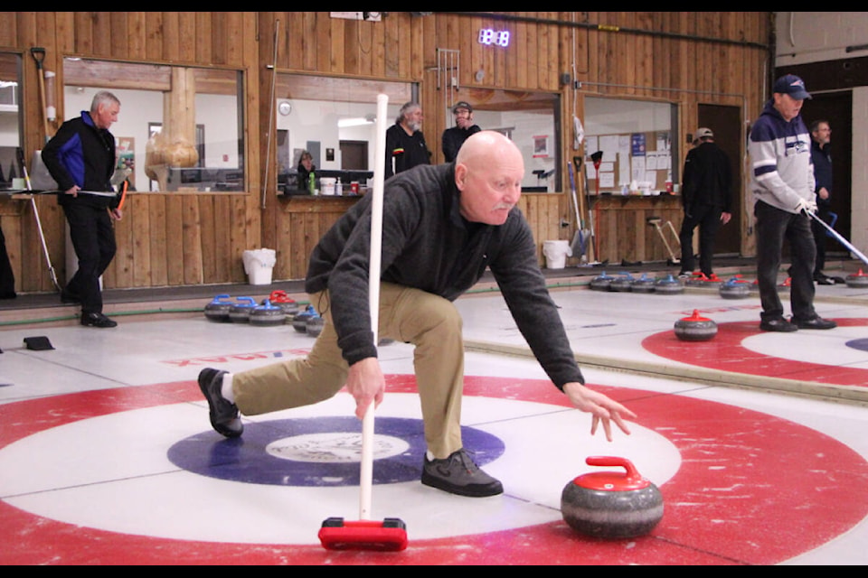 Tom Faulkner, from Sheridan Lake, releases the curling rock while competing in the 100 Mile Curling Club’s 2023 Men’s Bonspiel. (Patrick Davies photo - 100 Mile Free Press)