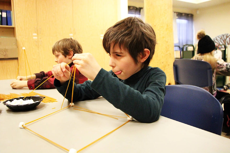 Luke Hogan sticks his tongue out as he assembles a pyramid using marshmallows and pieces of spaghetti. (Patrick Davies photo - 100 Mile Free Press)
