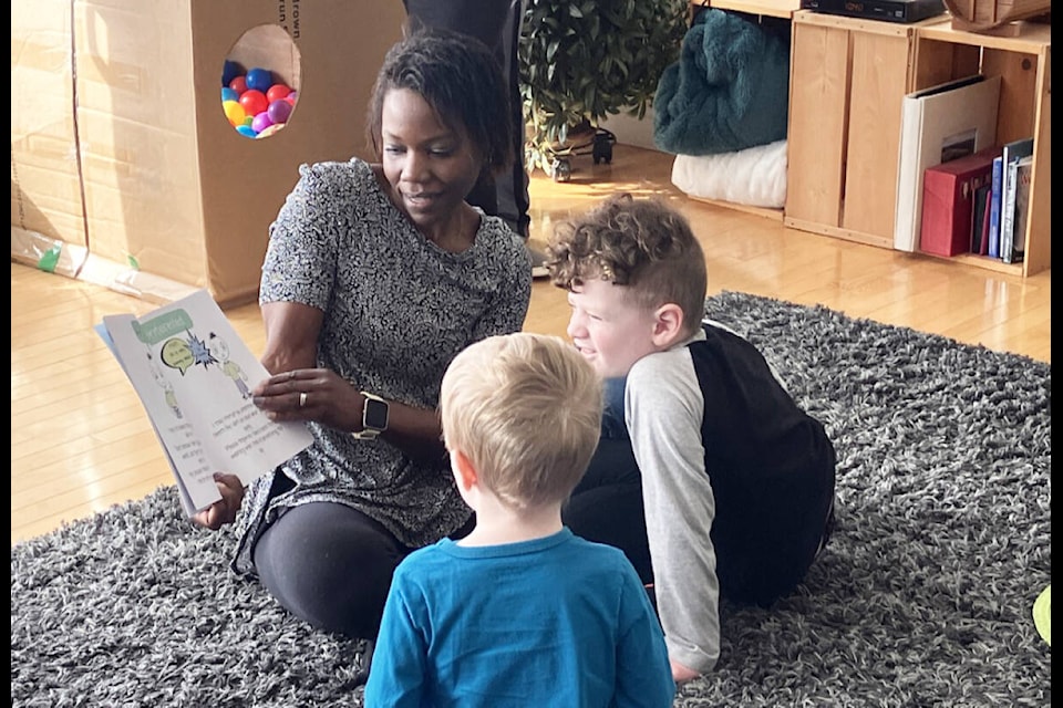 Addilyn Ratcliff, program coordinator for Blue Sky Autism reads a story as Noah Duncan, 3 (L) and Orrin MacPherson, 5 listen. (Fiona Grisswell photo - 100 Mile Free Press)