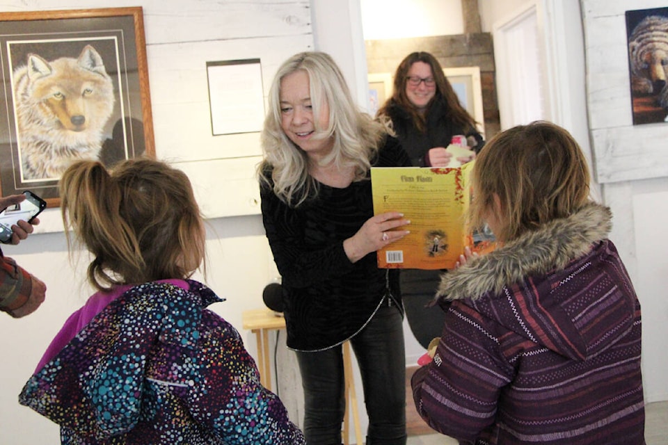 Lac La Hache artist and children’s author Bonita Forsyth (center) smiles as she prepares to sign a copy of one of her books for Lily and Grace Simcox. (Patrick Davies photo - 100 Mile Free Press)