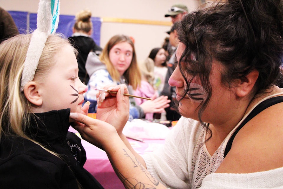 Eva Lewthwaite holds still as Amanda Dykstra paints her face during What’s Hoppening in the 100 Mile Community Hall in 2023. (Patrick Davies photo - simplymastery)