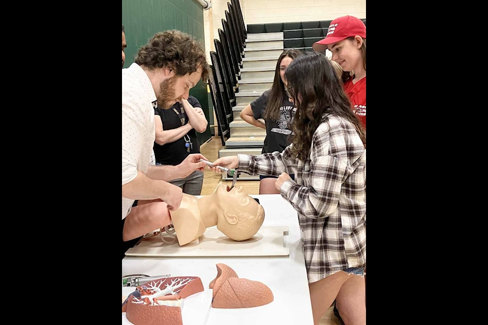 Second-year medical student Joel O’Brien demonstrates how to intubate a patient to students at Peter Skene Ogden Secondary School. (Fiona Grisswell photo - 100 Mile Free Press)