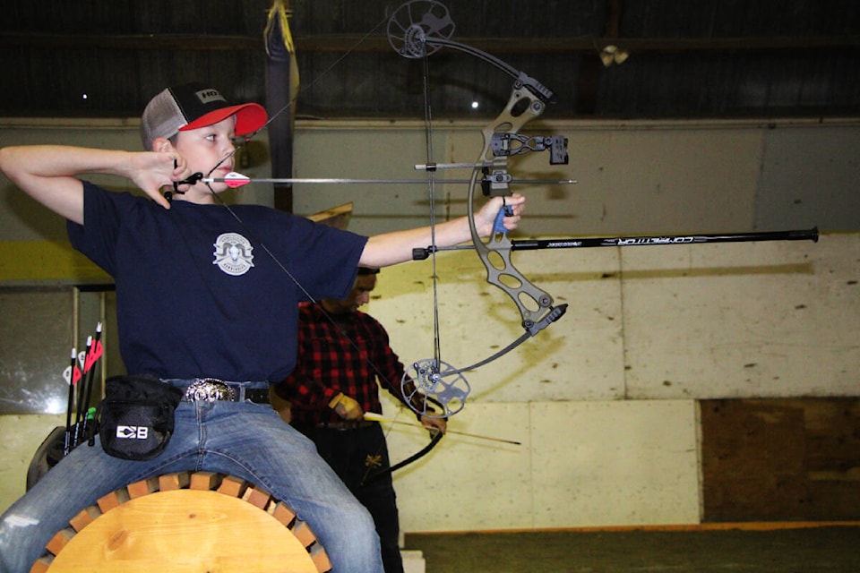 Brendan Douglas straddles a log as he takes aim at a target set up for the Big Horn Archery Club’s annual Indoor 3D Shoot. (Patrick Davies photo - 100 Mile Free Press)