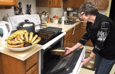 Barb Giraud places a loaf of banana bread into her oven