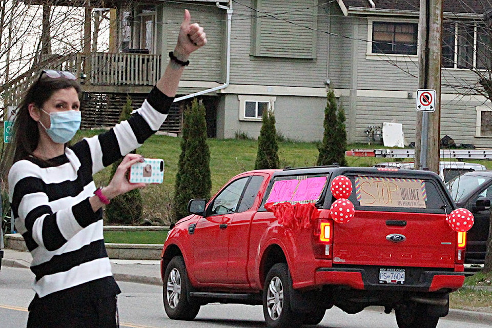 A supporter waves on the honking vehicles as they exit Mission Memorial Hospital. Patrick Penner / Mission Record.