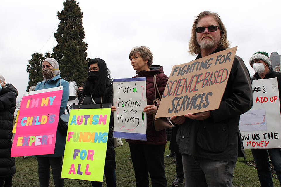 David Bridges, right, and others participate in a rally outside the B.C. legislature Wednesday (Feb. 9) calling for the province to end its planned phase-out of individualized autism funding. (Jake Romphf/News Staff)