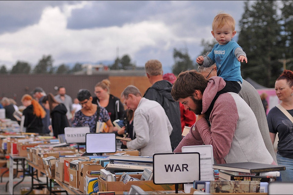 Brendan Van Beek of Agassiz carries his 21-month-old son on his shoulders while shopping for books during the one-day Chilliwack Rotary Outdoor Book Sale on Saturday, Aug. 27, 2022. (Jenna Hauck/ Chilliwack Progress)