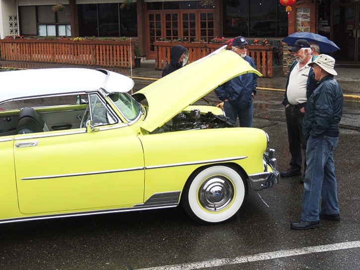 Car show enthusiasts gather around a 1952 Chev Bel Air.