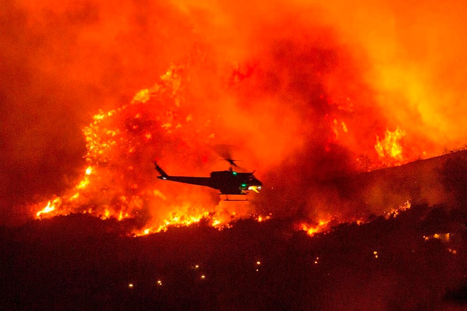 A helicopter prepares to drop water at a wildfire in Yucaipa, Calif., Saturday, Sept. 5, 2020. Three fast-spreading California wildfires sent people fleeing Saturday, with one trapping campers at a reservoir in the Sierra National Forest, as a brutal heat wave pushed temperatures into triple digits in many parts of state. (AP Photo/Ringo H.W. Chiu)